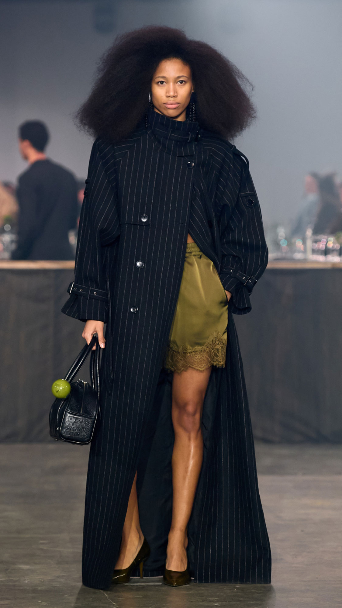 Model in langem schwarzem Nadelstreifenmantel bei der GESTUZ Autumn/Winter 2026 Fashionshow