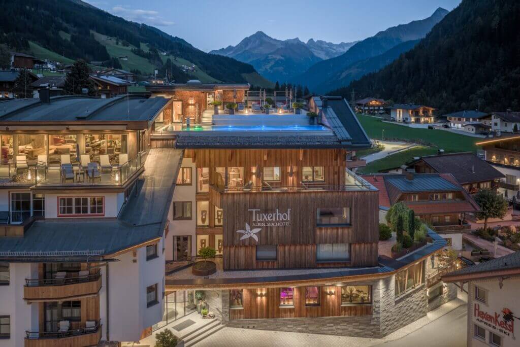 Alpin Spa Hotel Tuxerhof mit beleuchtetem Rooftop-Pool in der Abenddämmerung